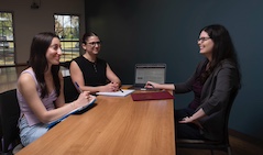 Three women sit at a table in discussion.